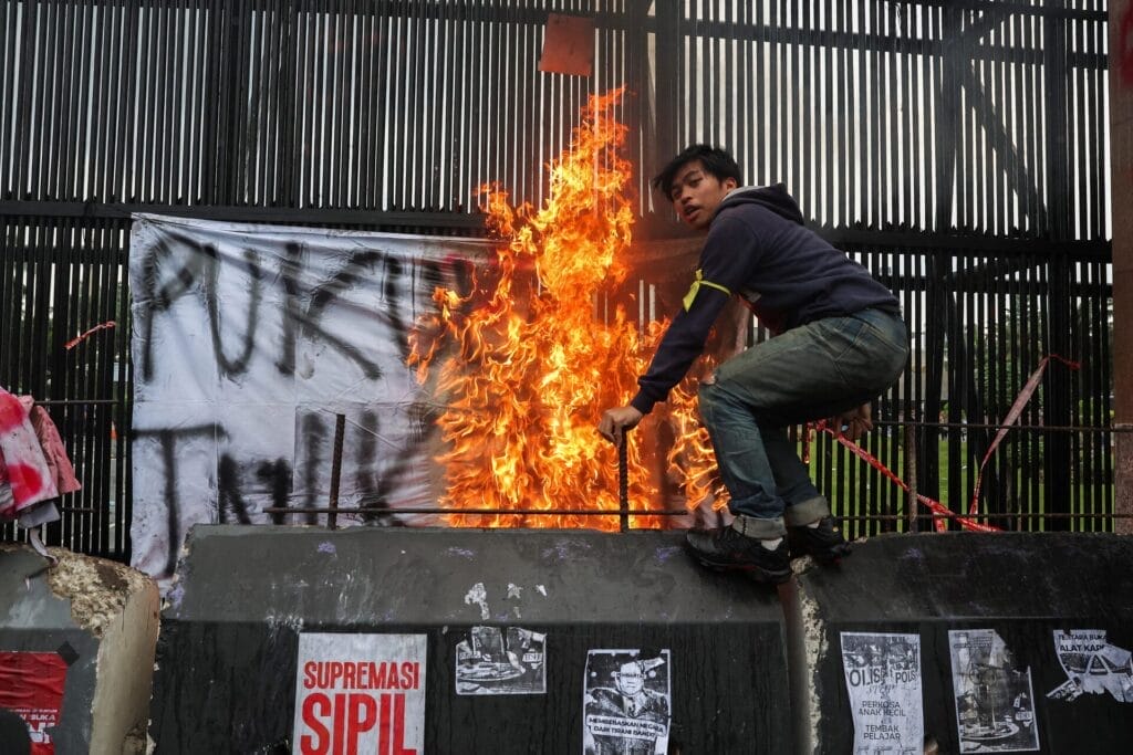 Um homem fica em cima de uma barreira de concreto durante um protesto em frente ao Parlamento da Indonésia, contra as revisões da lei militar do país, que alocará mais cargos civis para oficiais militares, em Jacarta, Indonésia, 20 de março de 2025. REUTERS/Ajeng Dinar Ulfiana.
